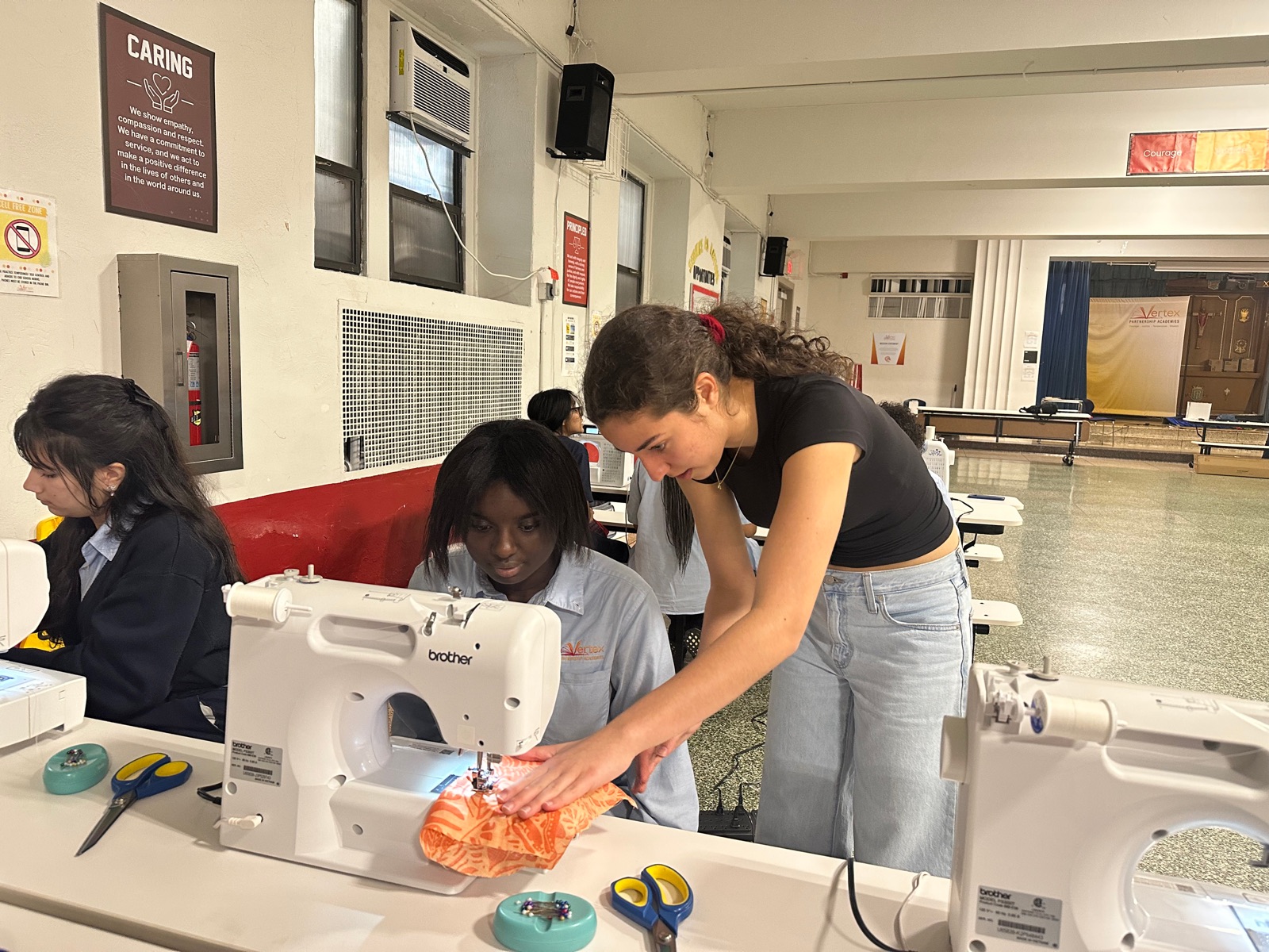 Noa guiding a student's fabric through a sewing machine