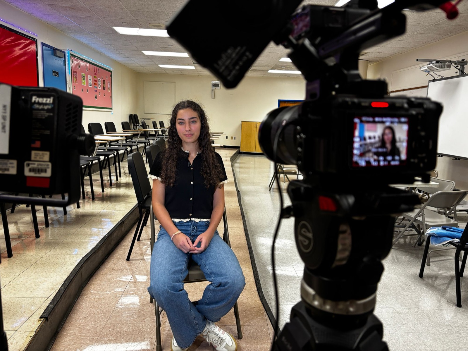 Noa seated in a classroom in front of a NY1 News camera